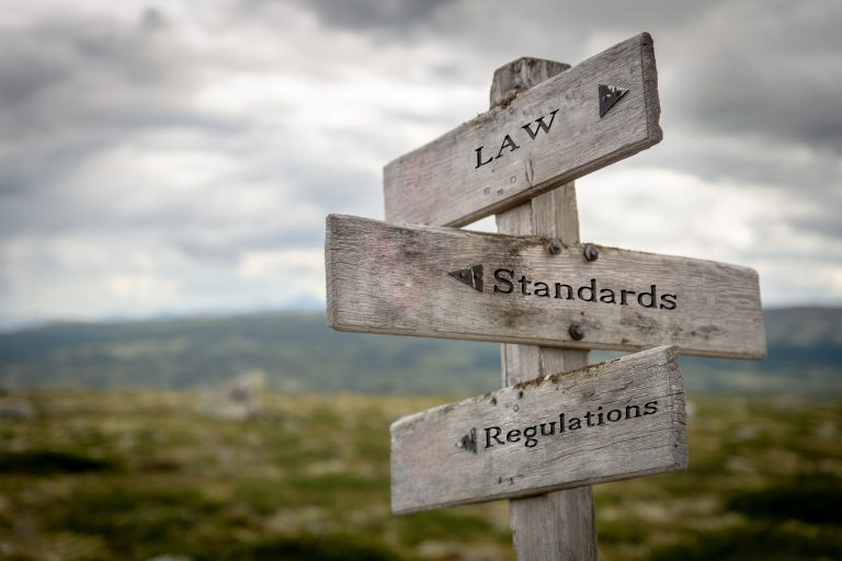 Kolme kylttiä jotka osoittavat eri suuntiin. Law, standards ja regulations
